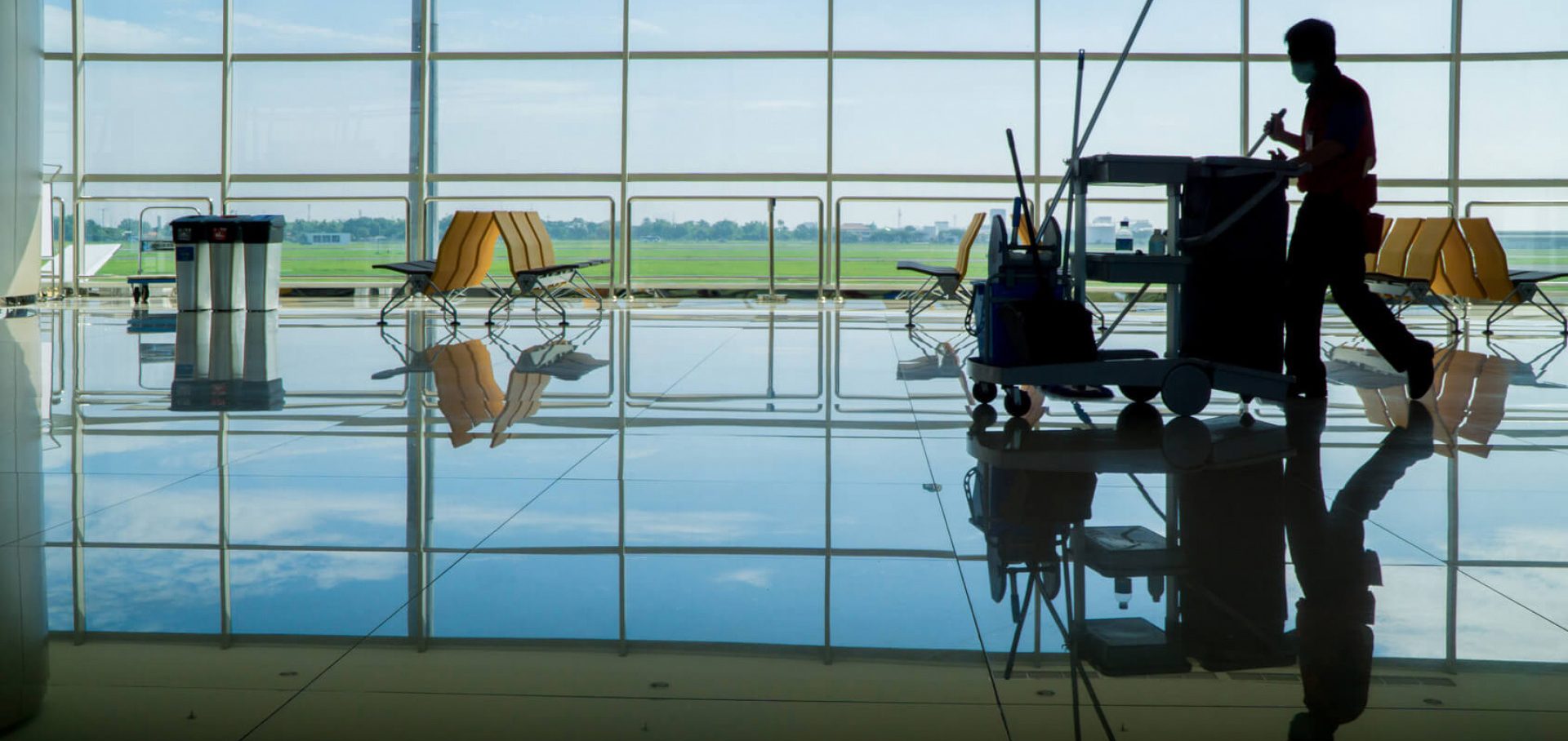 Reinigungsmitarbeiter schiebt einen Wagen über den gläsernen Boden in einem Flughafen.
